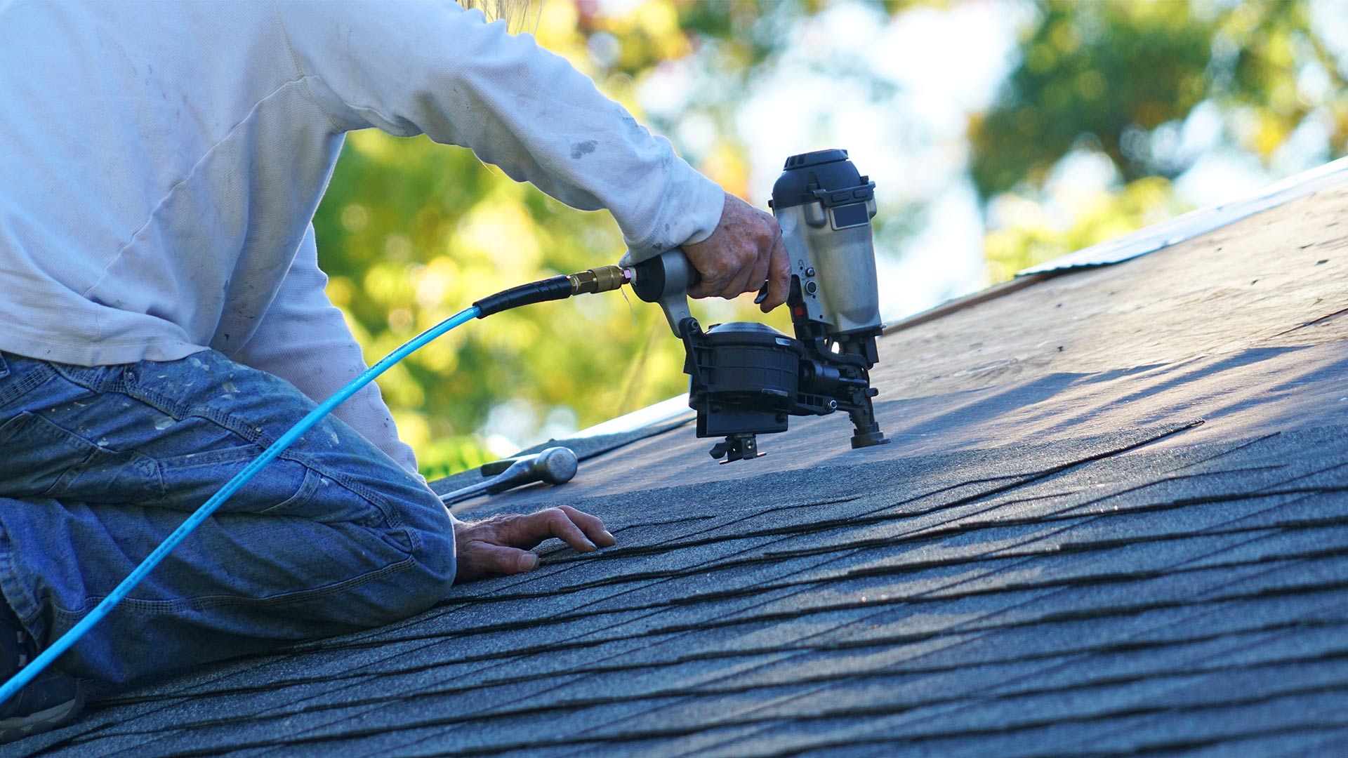 contractor installing asphalt shingles roof with nailgun close up at property corryton tn